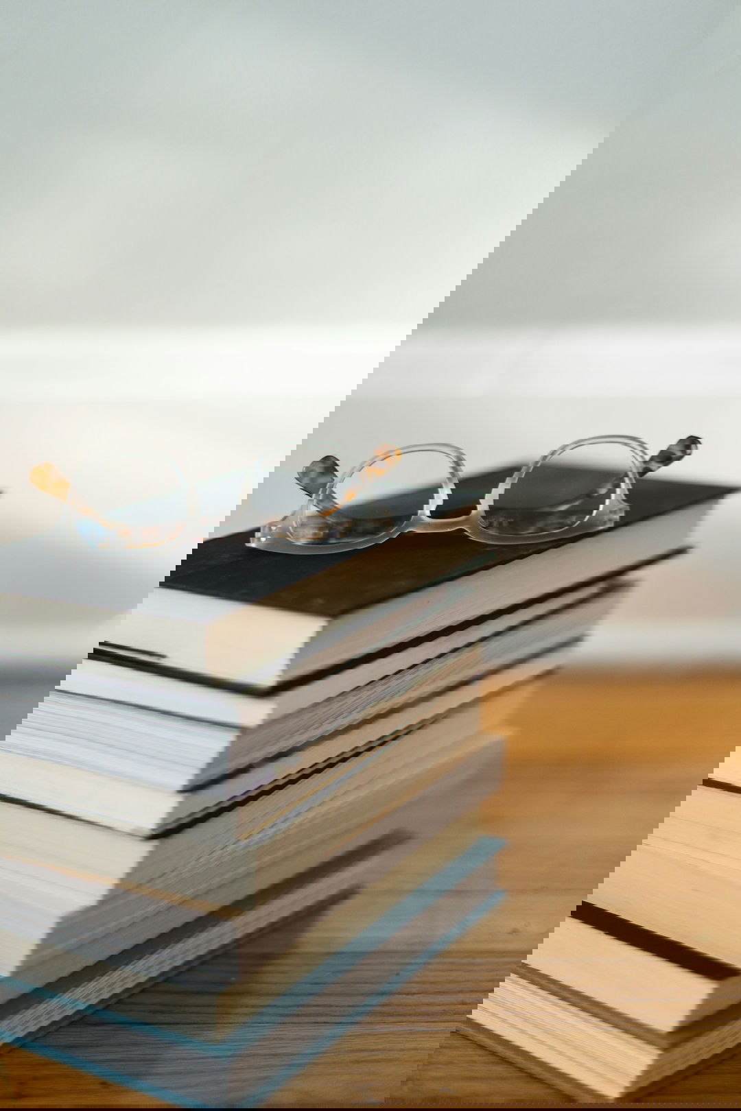 clear framed eyeglasses on top of pile of books